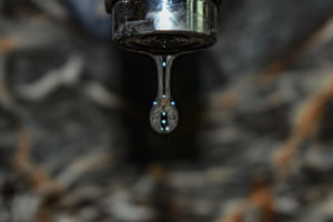 Fotografia d'una gota d'aigua pendent de caure d'una aixeta